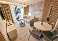 Moderan hotelski apartman sa dnevnom sobom, sofom, stolom i pogledom na balkon