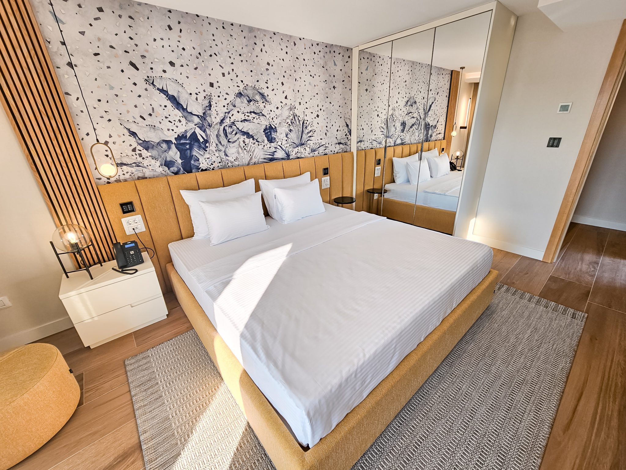 Moderna hotelska soba sa dvokrevetnom posteÑ™om, drvenom ogradom kreveta i umetniÄkim zidnim motivom sa Å¾ivotinjama